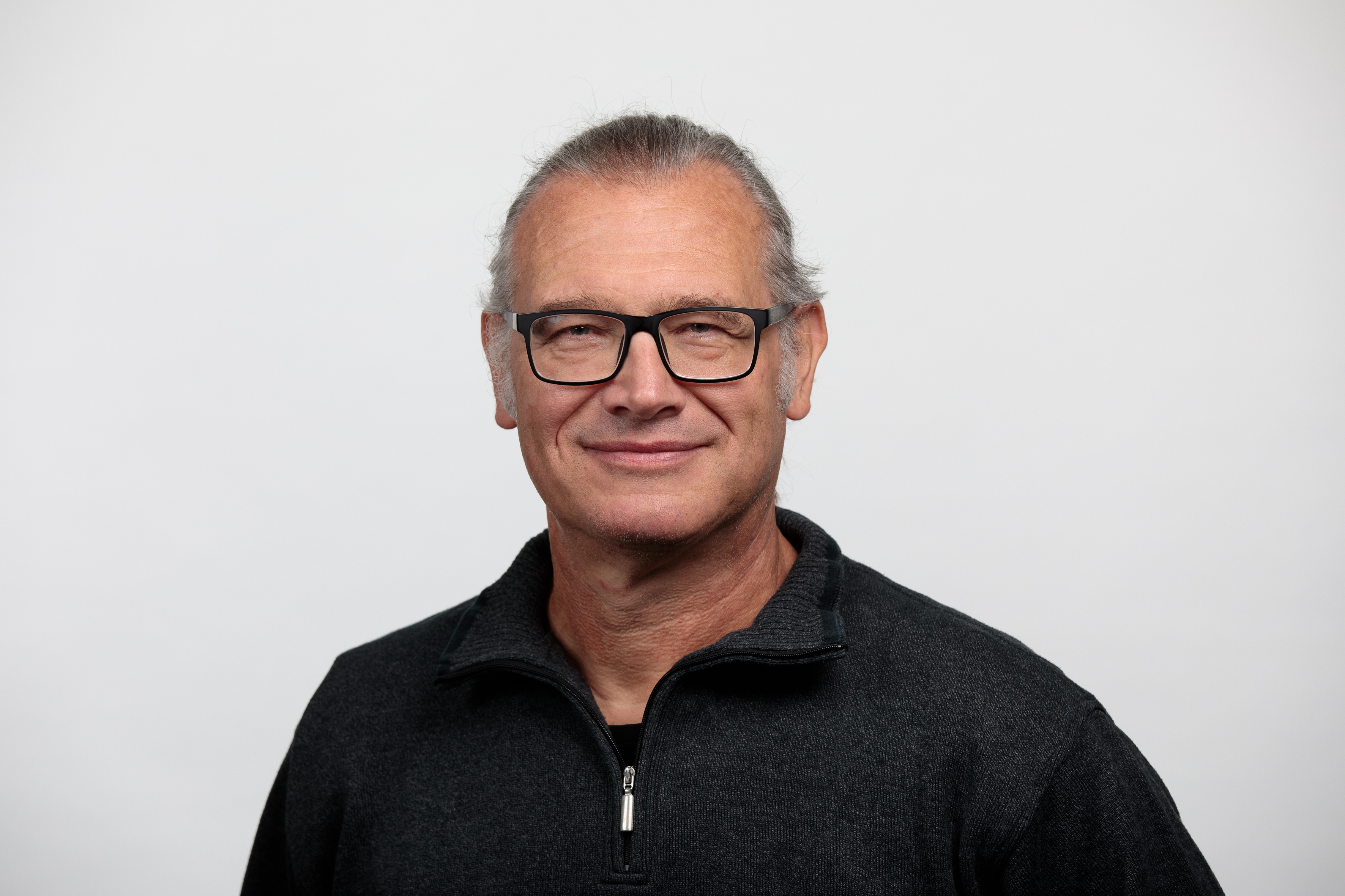 Portraitbild eines weissen Mannes mit langen grauen Haaren und Brille